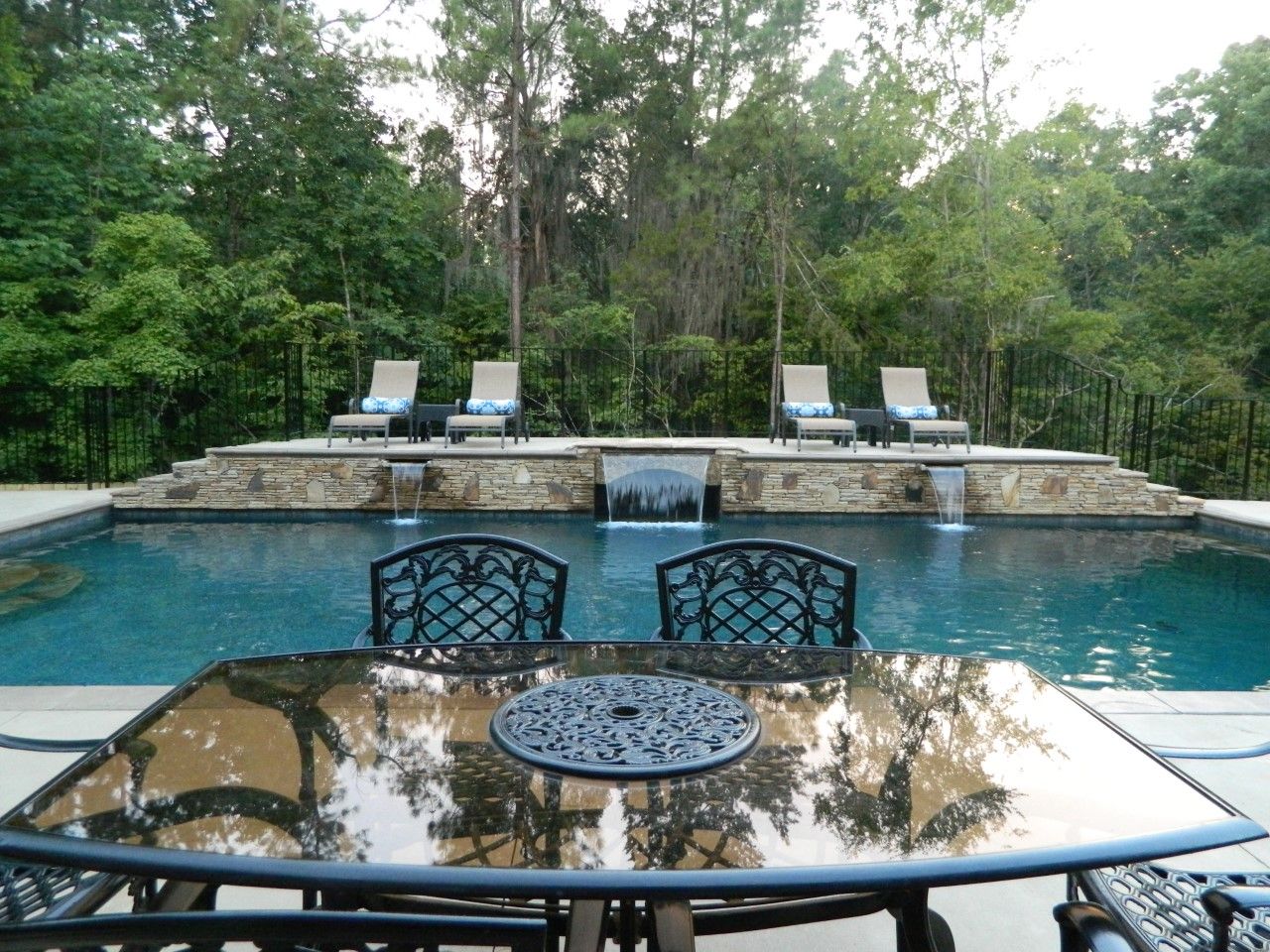 A glass outdoor table and chairs near the pool